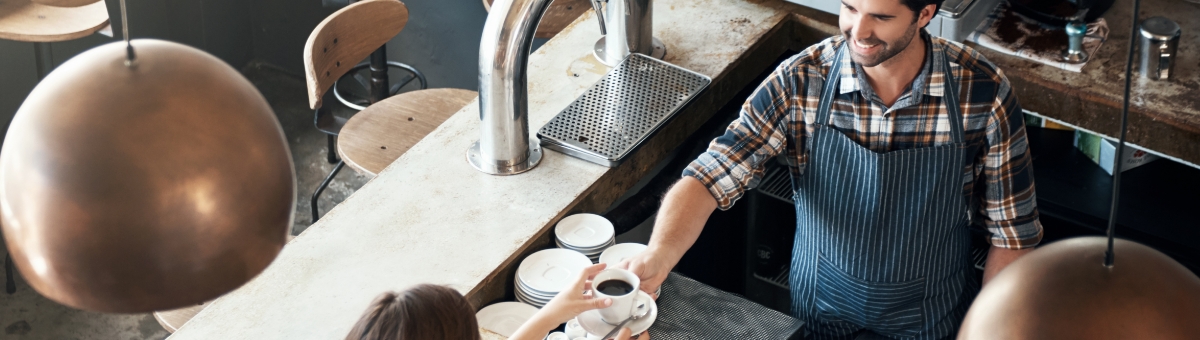 ภาพ: พนักงานยื่นกาแฟให้ลูกค้าที่เคาน์เตอร์ร้านกาแฟ
