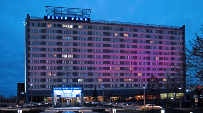 An image of River Park Hotel building exterior lighted in purple during nighttime