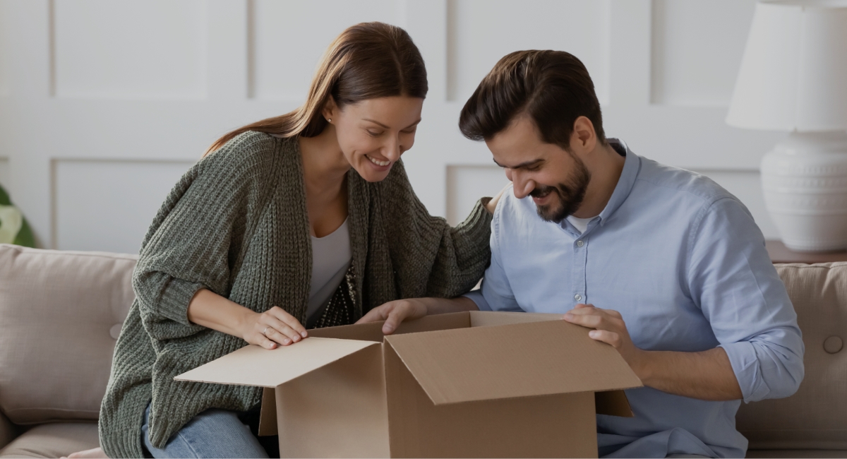 Imagen de un hombre y una mujer abriendo juntos una caja de cartón