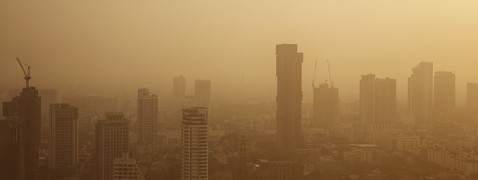 Eine Abbildung, die PM2,5-Feinstaub und eine in gelben Sand eingehüllte Stadt zeigt.