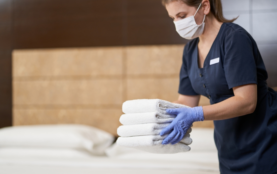 An image of a female staff replenishing towels in the guest room.