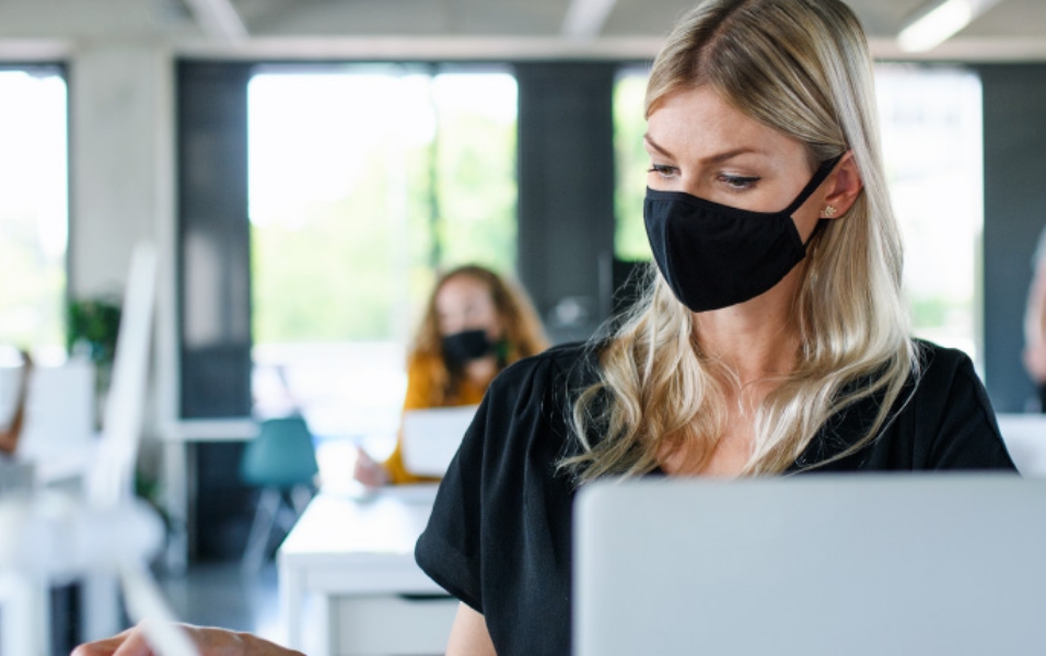 An image of a female employee working with a facial mask on.