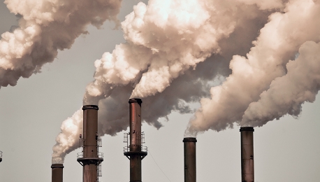 Una imagen de un grupo de chimeneas donde se alza humo y materia particulada PM 2.5.