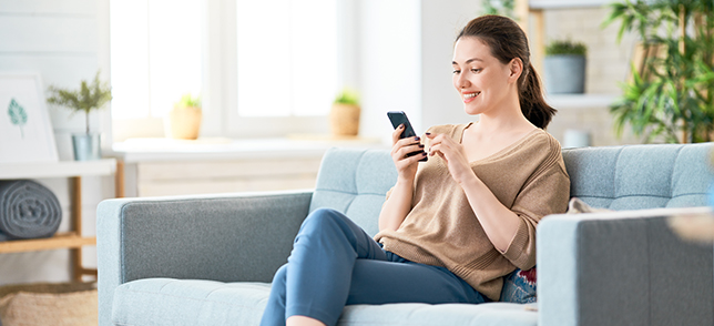 A women sitting on sofa while using her smartphone