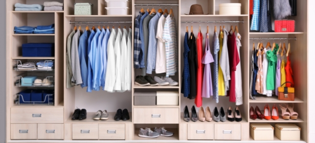 A photo of a closet full of clothes but well organized.