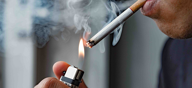 A close up photo of a person lighting the cigarette on fire