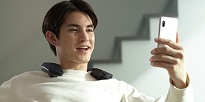 A person talking over the phone wearing the neck speaker.