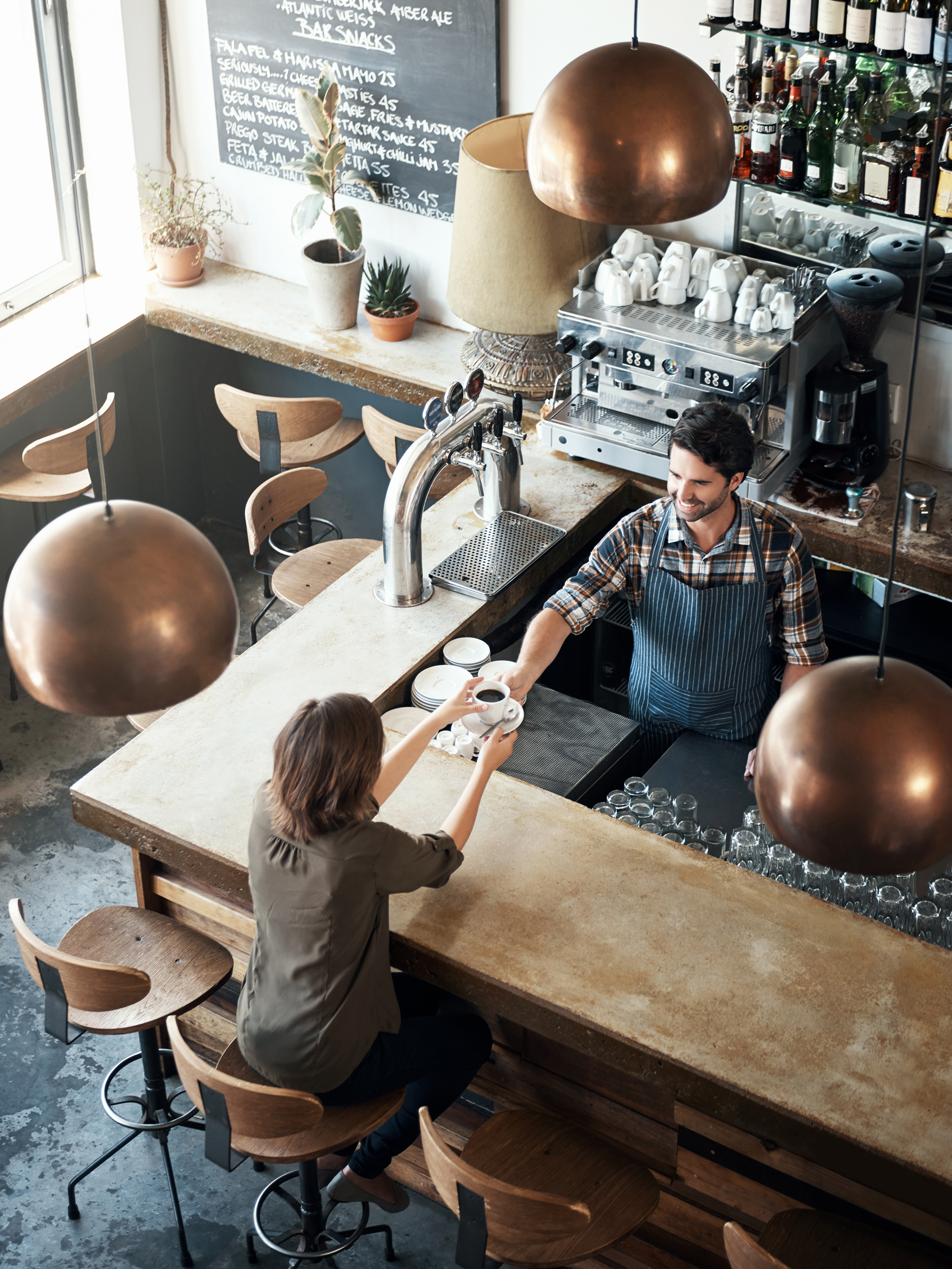 image: A staff handing coffee to customers at the coundter of a café