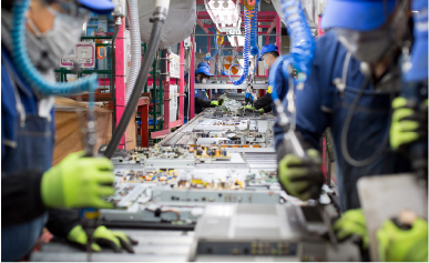 Valokuva: PETECin tehtaan linjalla työntekijät käyttävät ruuvinväännintä uudelleenkäytettävien osien irrottamiseen.