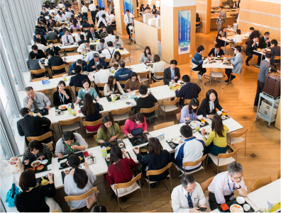 Foto: Panasonicu ettevõtte kohviku üldvaade. Suur hulk inimesi on kohvikus söömas.
