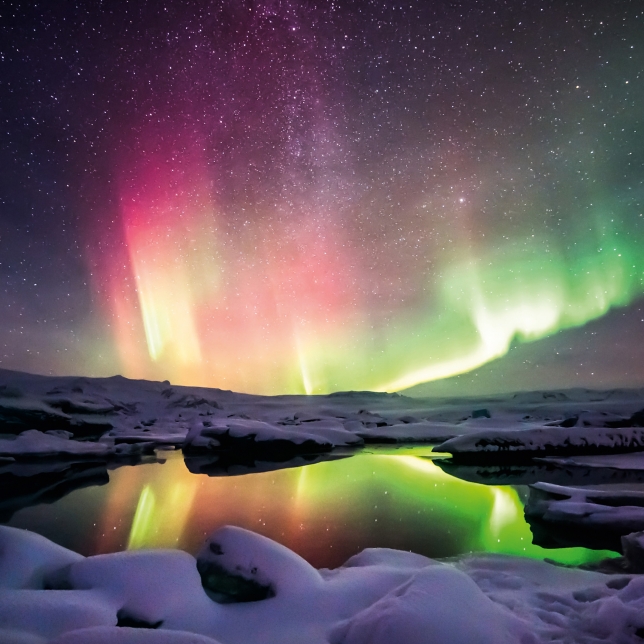 Polarlicht in einem schneebedeckten Gebiet und Spiegelung des Lichts in einem See