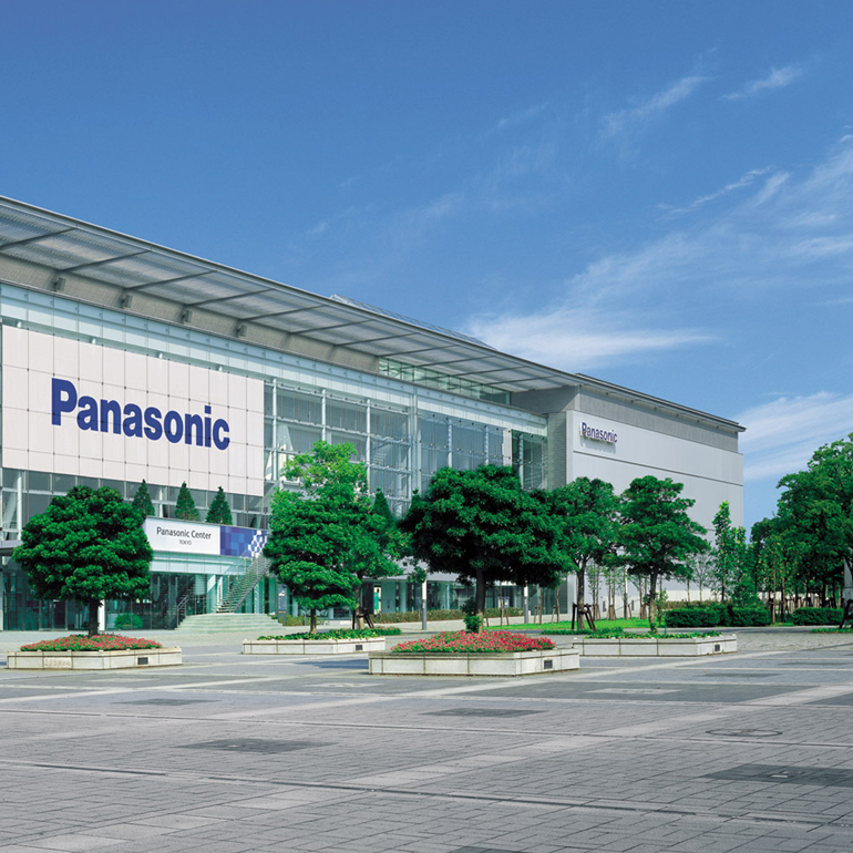 Exterior of a Panasonic building with trees and bushes in front.
