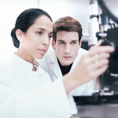 Two individuals in lab coats are working with laboratory equipment