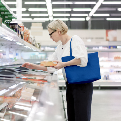 Una persona seleccionando artículos de una vitrina refrigerada en una tienda de comestibles.