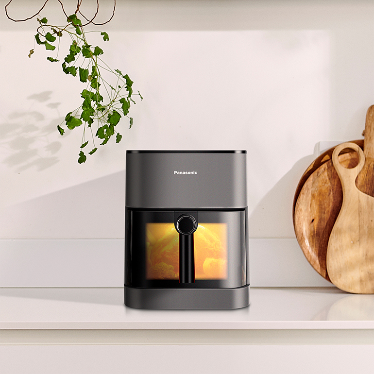 Friteuse sans huile sur un comptoir avec des objets décoratifs en arrière-plan.