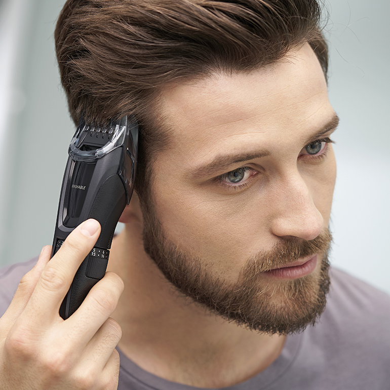 Person som använder en elektrisk rakapparat med texten Skägg- och hårtrimmer med hög precision.