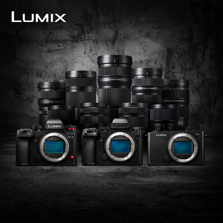 Collection d'objectifs d'appareils photo Lumix et trois appareils photo disposés devant un fond sombre et texturé.