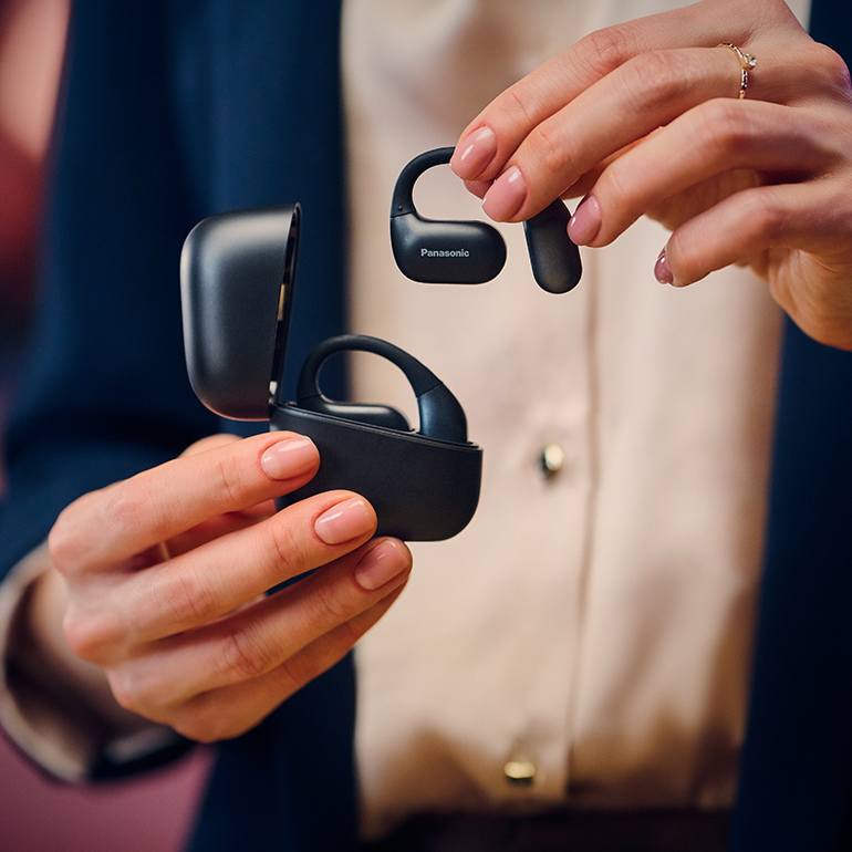 Person hält ein Paar schwarze kabellose Ohrhörer