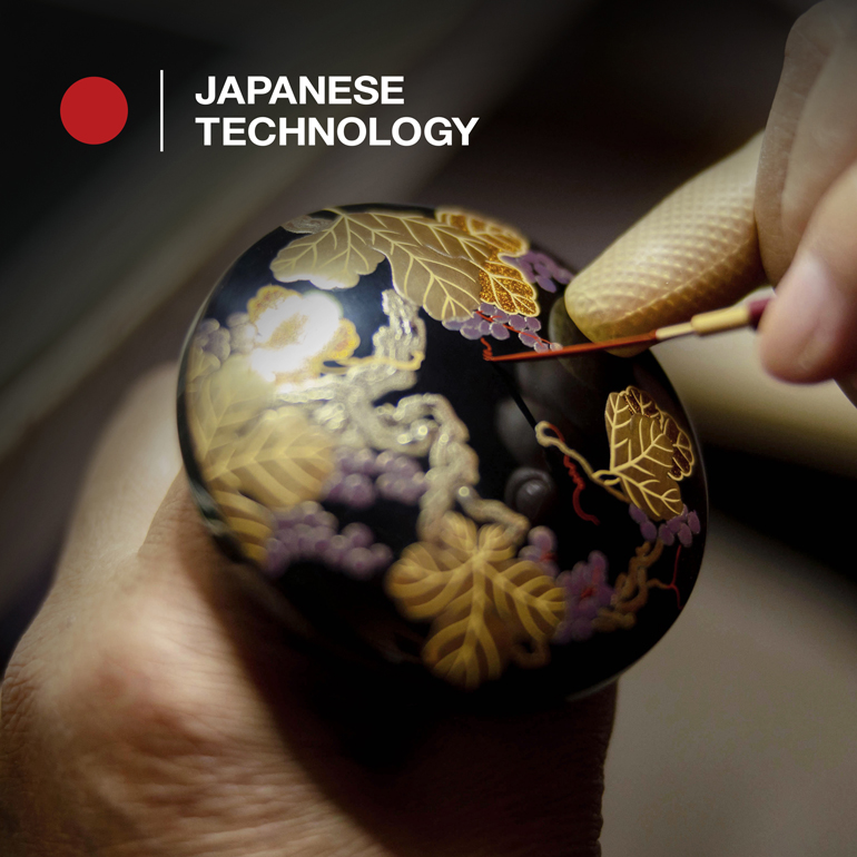 Close up image of a Japanese craftsman painting the lid of a wooden bowl.