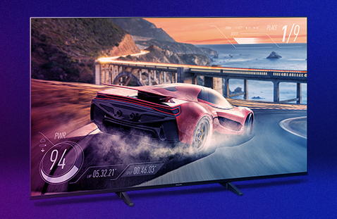 Product image of the JX940 LED TV in front of a colored background. On the screen you can see a car racing video game.