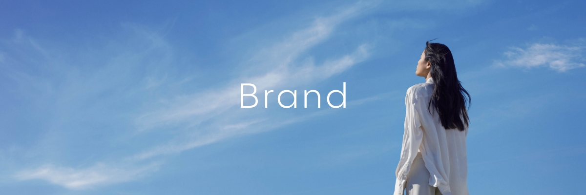 An image of a woman looking up the blue sky while being feeling the breeze of the wind.