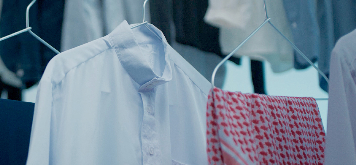 Close-up photo of a Middle Eastern thobe and scarf on hangers amongst many other clothes.