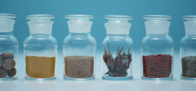 Various herbs and spices in glass jars for testing.