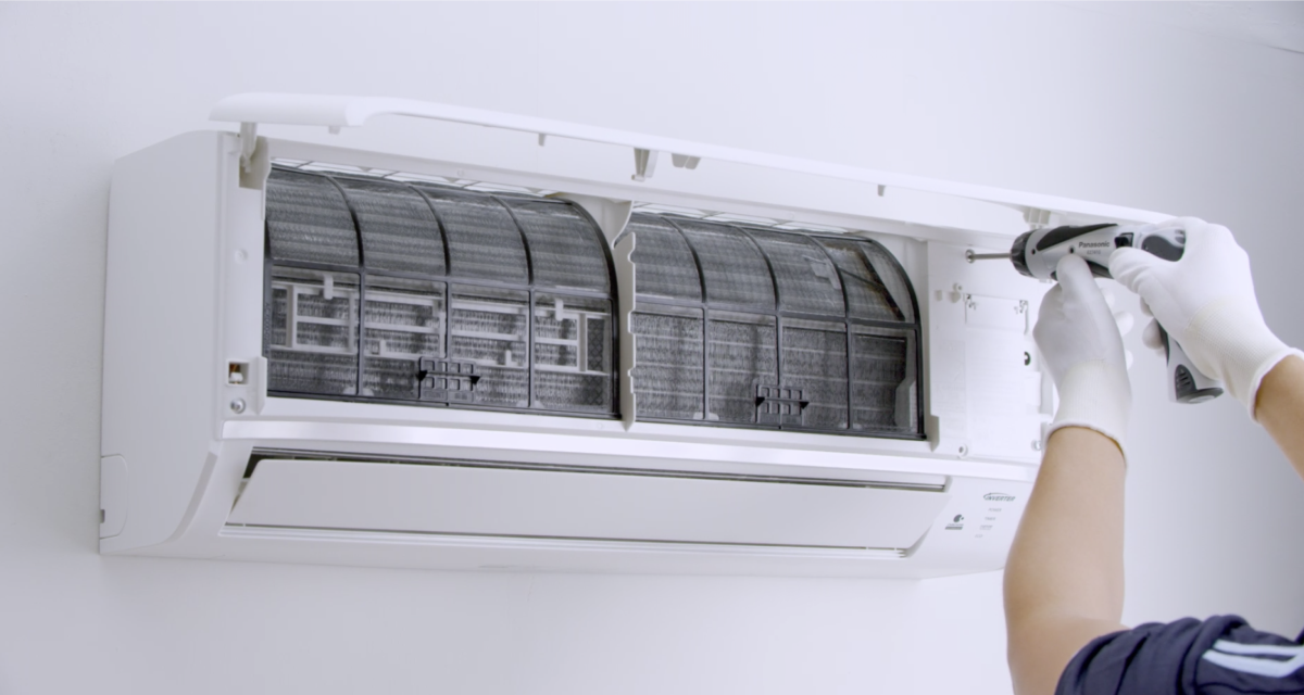 Serviceman using an electric driller to service the aircond