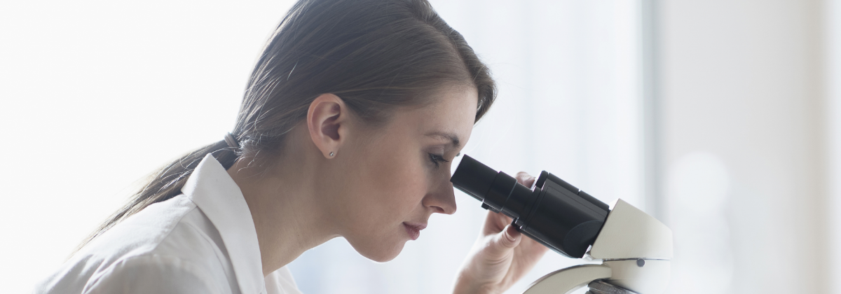 Female researcher looking through a microscope: image of Verification