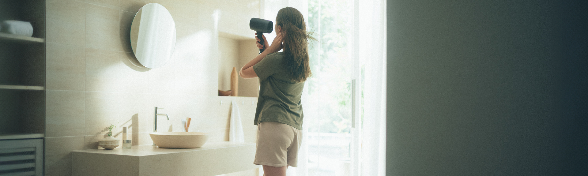 Top Banner: A woman drying her hair with a compact, stylish hair dryer in a sunny bathroom.