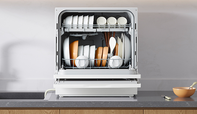 Photo of a tabletop dishwasher, door open and filled with dishes, on a kitchen counter.