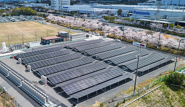 Aerial photo of the RE100 Demonstration Facility at the Panasonic Corporation Kusatsu Factory, featuring many rows of solar panels and fuel cells.