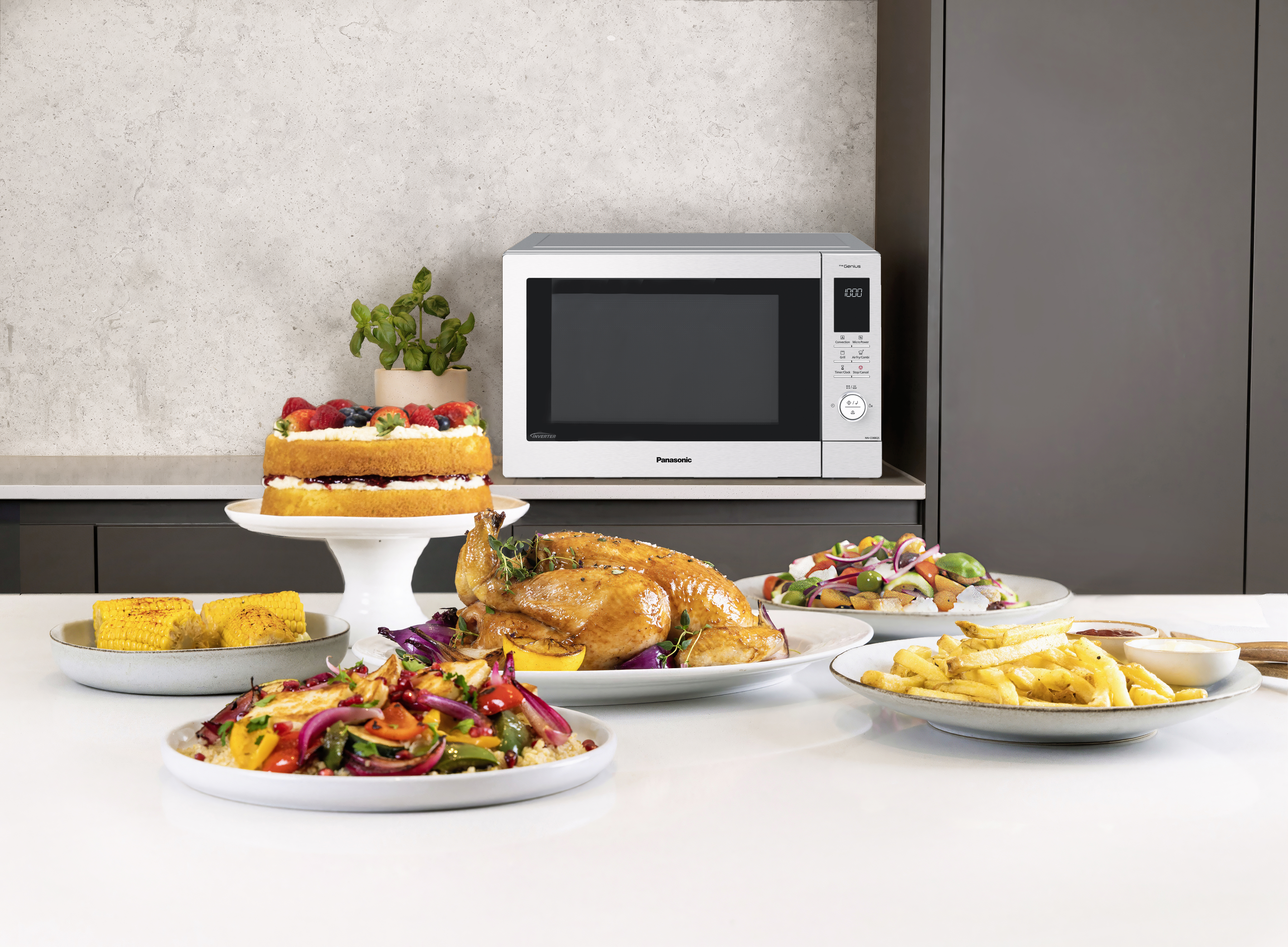 NN-CD88-mikrobølgeovn med kombiovn og airfry med et udvalg af lækre retter, herunder stegt kylling, pommes frites, halloumi-salat og kage.