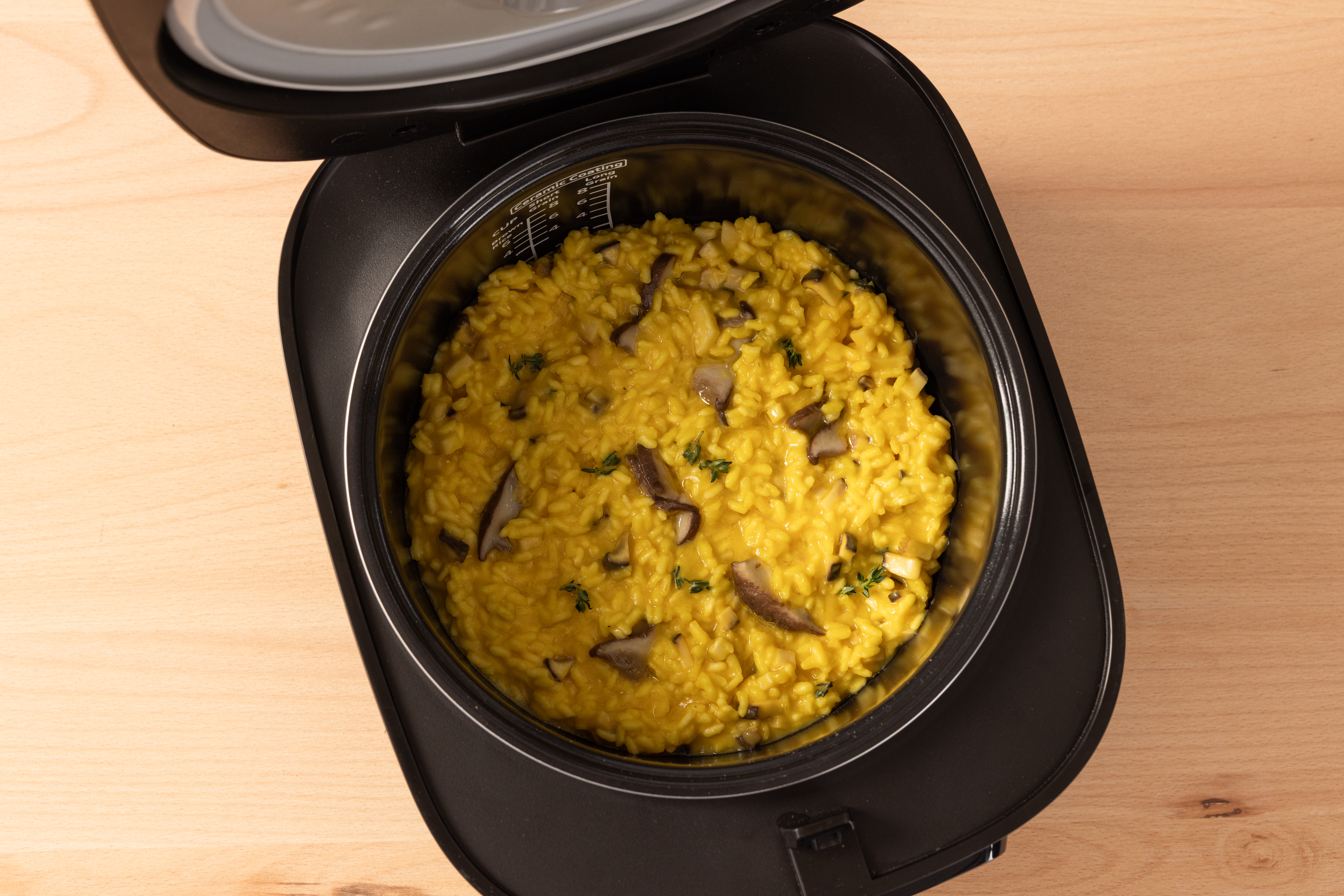 Slightly tilted top view of the SR-DA152KXE Rice Cooker in Black filled with risotto.