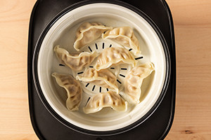 Top view of the SR-DA152KXE Rice Cooker in Black filled with dumplings, with the Steam Basket visible.