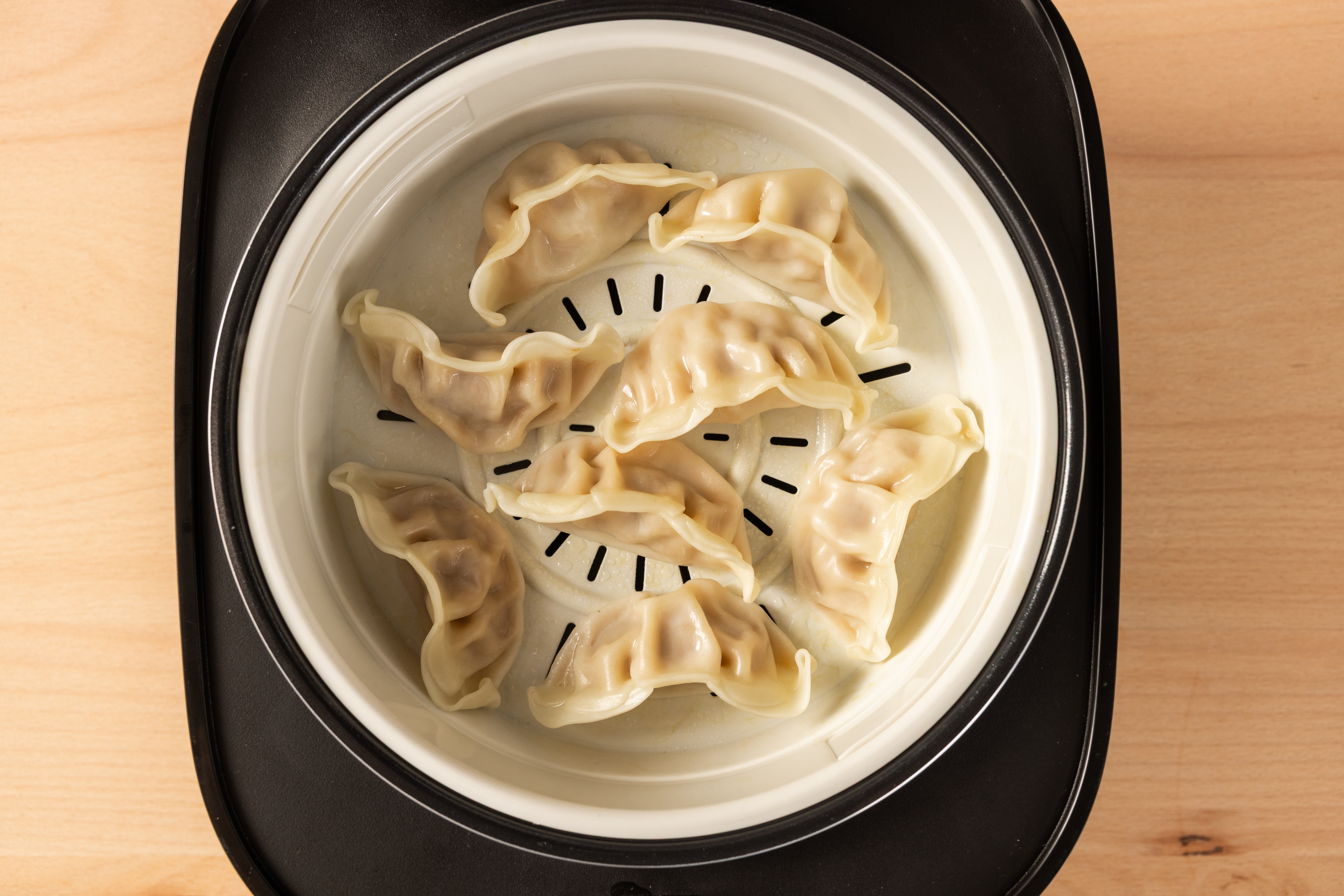 Top view of the SR-DA152KXE Rice Cooker in Black filled with dumplings, with the Steam Basket visible.