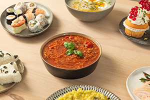 Tomato, basil, and lemon bulgur soup surrounded by various other dishes.