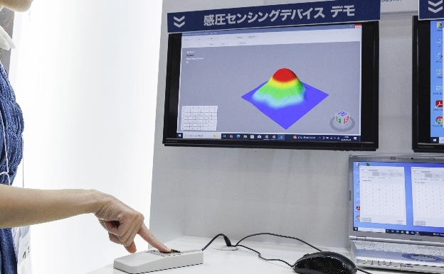 パッドに触れた圧力を画面表示する、感圧センシングデバイスの展示。画面上で3D表示され、触れた部分が隆起する