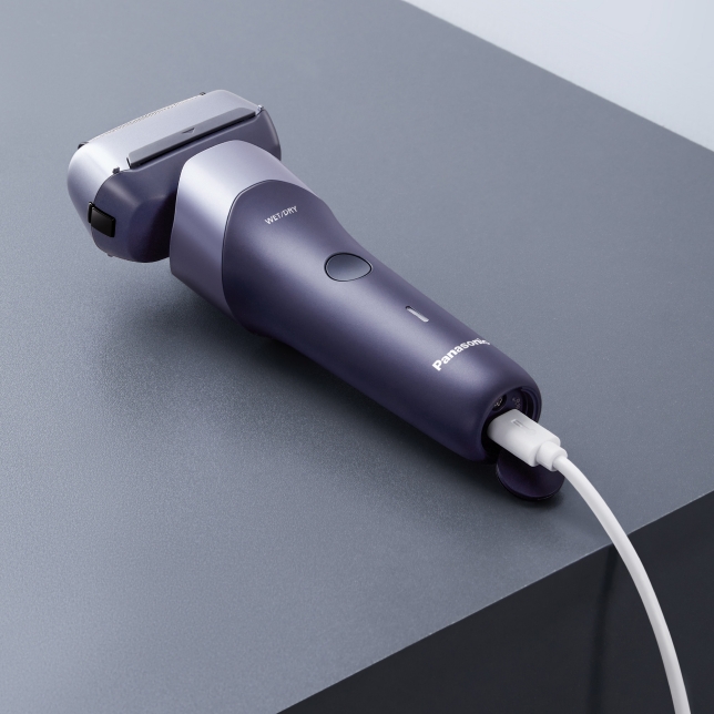 Rasoir présenté sur une surface avec le câble USB-C branché pour le recharger