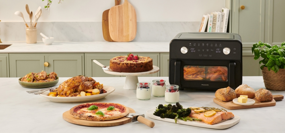 Panasonic Flex Air Fryer NF-BC1000 op een aanrecht met verschillende bereide maaltijden.