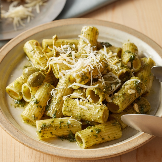 Draufsicht auf einen Pastateller mit geriebenem Käse, Kräutern und Gewürzen. Die Zutaten sind gleichmässig verteilt und sorgen für eine farbenfrohe, appetitliche Präsentation.