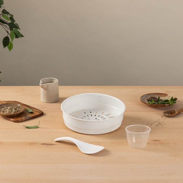 Steam Basket, Rice Scoop, and Measuring Cup surrounded by kitchen utensils, spices, and various food ingredients on a countertop.