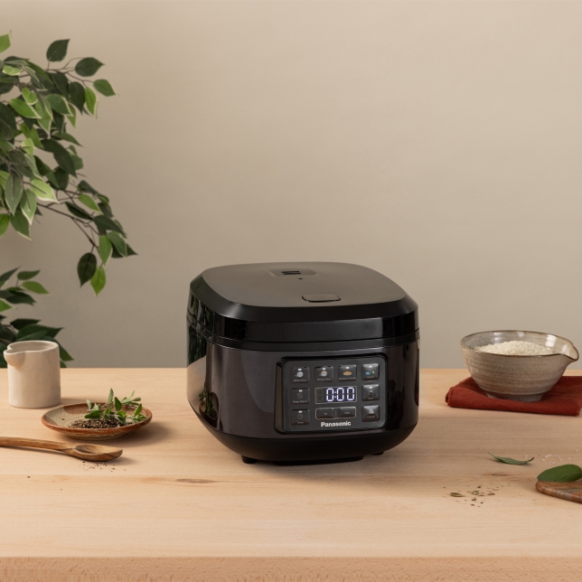 Front view of the SR-DA152KXE Rice Cooker in Black surrounded by spices and kitchen utensils.