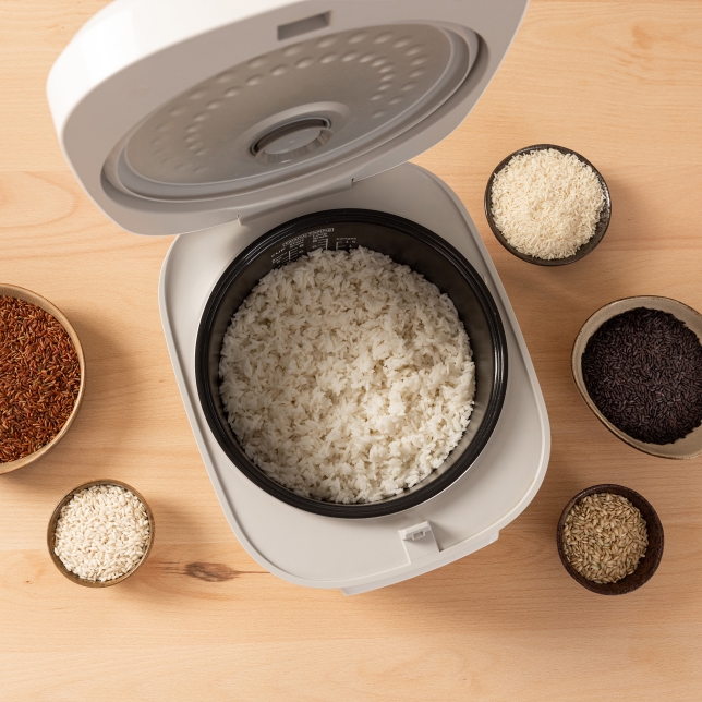 Top view of the SR-DA152WXE Rice Cooker in White, filled with cooked rice and surrounded by small bowls containing different types of rice.
