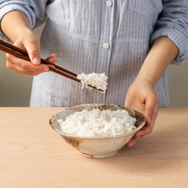 Vista superior de la olla arrocera en color blanco SR-DA152WXE, llena de arroz cocido y rodeada de pequeños cuencos que contienen diferentes tipos de arroz.