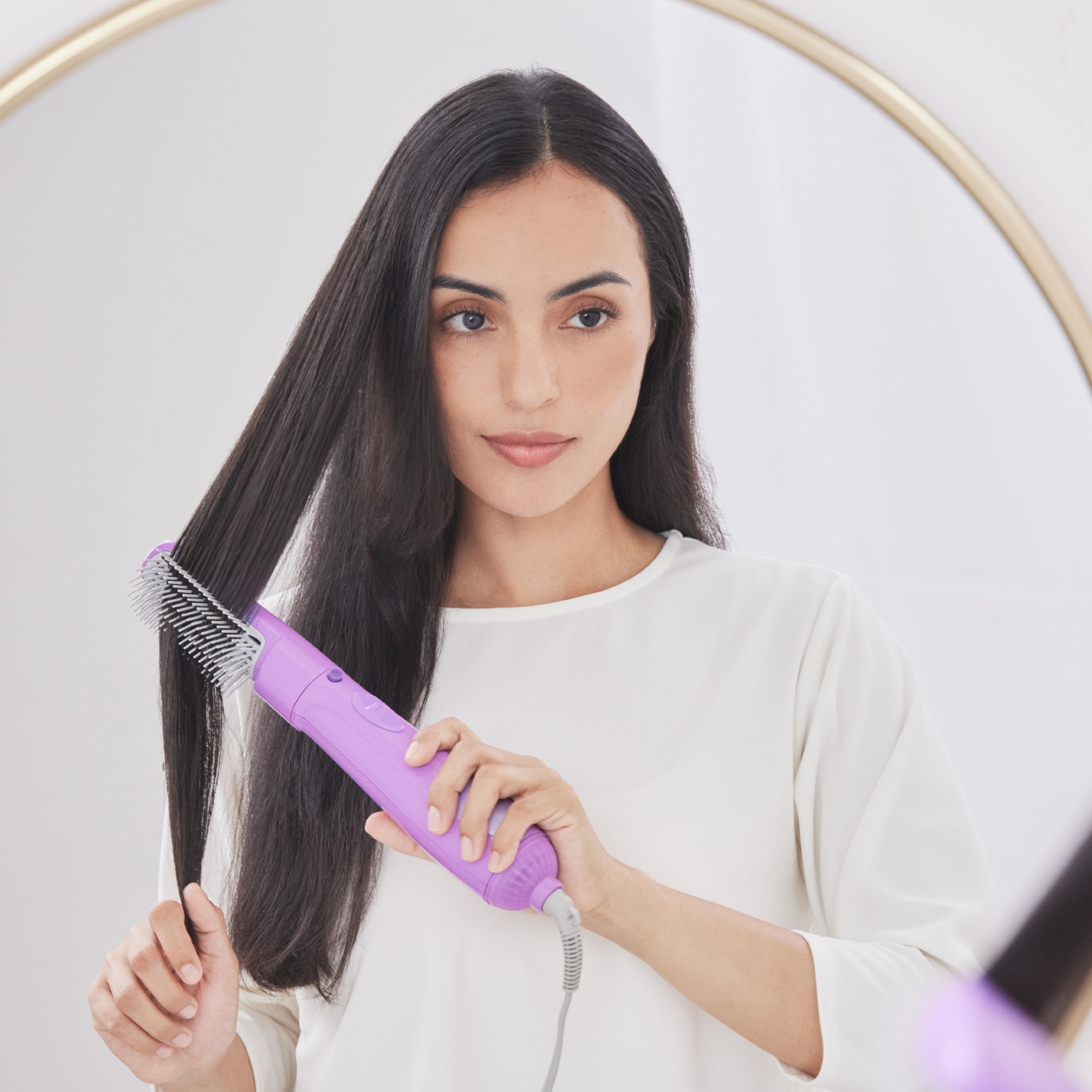 A woman with long, smooth dark hair using Panasonic hair styler with blow brush.