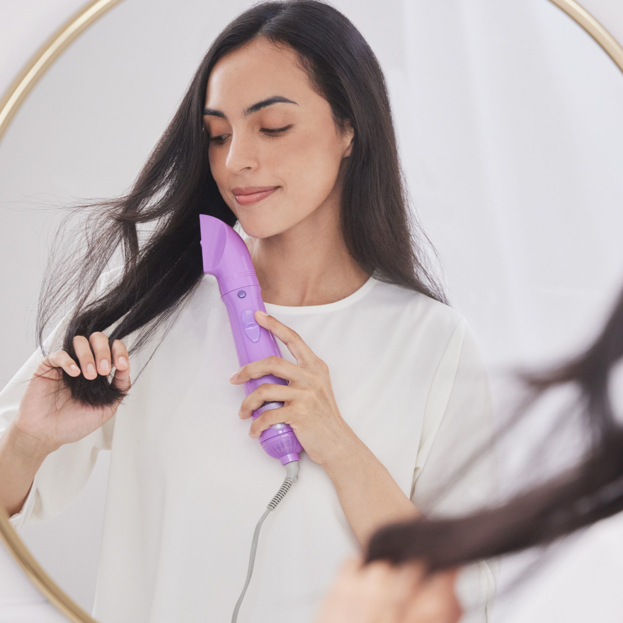 A woman with long, smooth dark hair using Panasonic hair styler with sim nozzle attachment to blow dry hair.