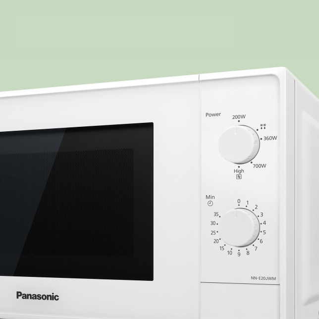 Close-up van het bedieningspaneel van een witte Panasonic NN-E20JWMEBG magnetron. Deze magnetron heeft twee draaiknoppen: de bovenste voor het selecteren van het vermogen (hoog, medium, laag) en de onderste voor het instellen van de timer in minuten. De deur is voorzien van een zwart kijkvenster.