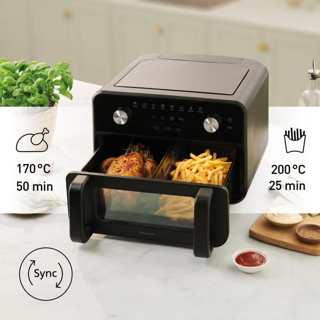 Panasonic Flex Air Fryer NF-BC1000 visas med två tillagningszoner som används till kyckling och pommes frites.  Till vänster visas ikonen för stekning med inställningen ”170 °C 50 min”, och till höger visas en Air Fryer-ikon med inställningen ”200 °C 25 min”. En rund synkroniseringssymbol visas längst ner till vänster, vilket indikerar synkroniserad tillagning. Apparaten står på en köksbänk med örter, såser och köksredskap i bakgrunden.