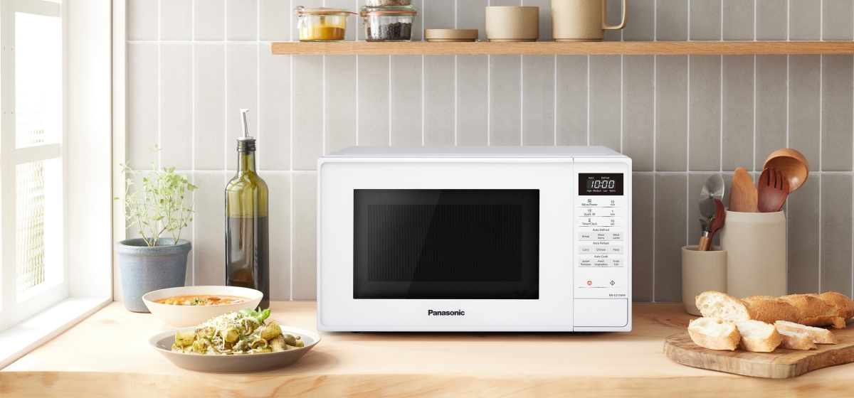 The white Panasonic NN-E27JWMBBQ microwave with the door open, showing the black interior and turntable. It has two control knobs on the right side for adjusting time and power. Dimensions and capacity are displayed next to the appliance.